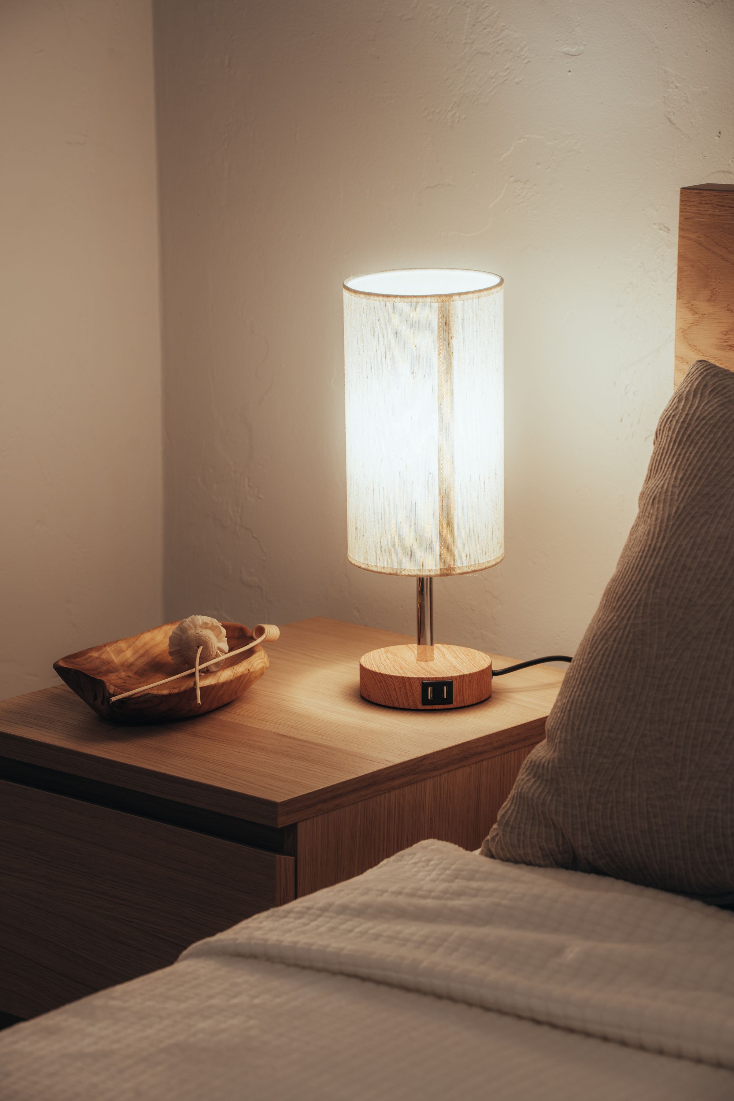 A lamp lit on a bedside table in a quiet room at night.